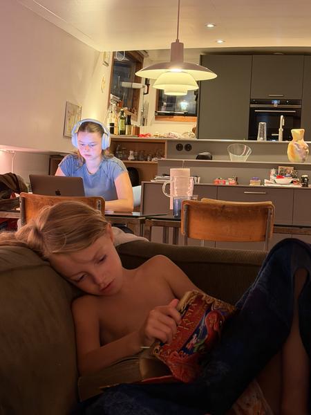 This photo captures a cozy indoor scene in Oudeschans, Uilenburg, Amsterdam, where two individuals are engaged in quiet activities